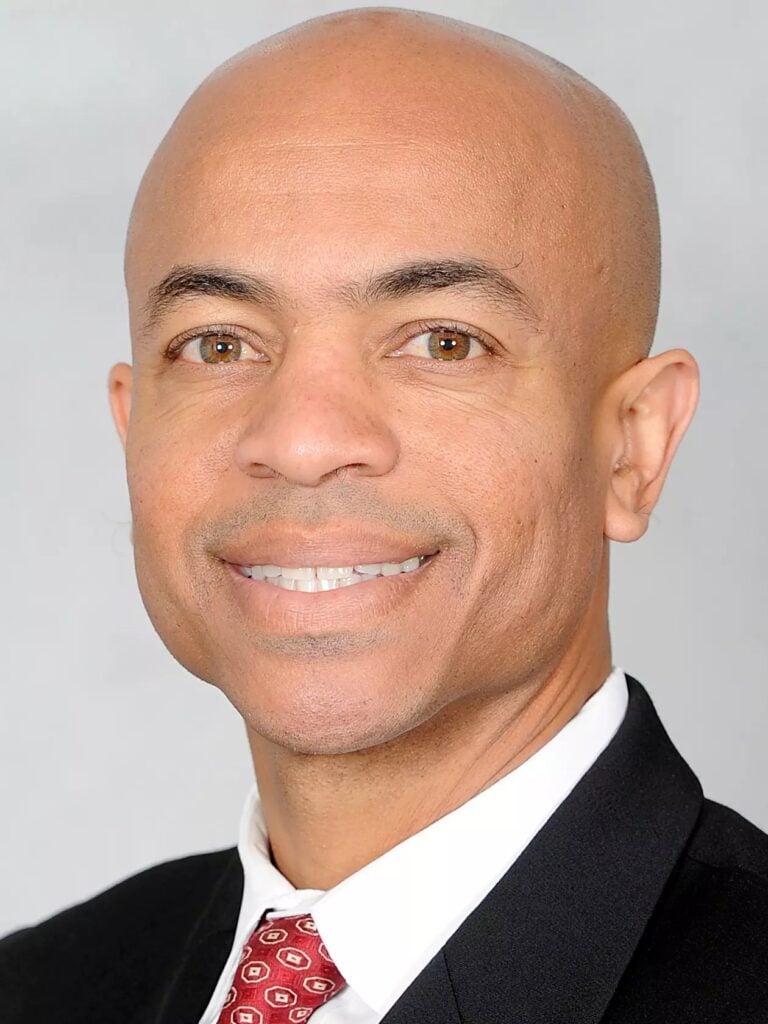 Professional headshot of a smiling man in a suit and tie.
