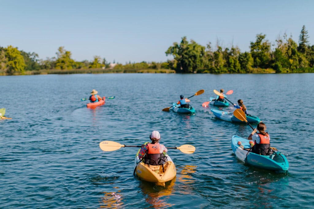 Kayakers paddling on a calm lake in Lodi, CA during sunny weather.