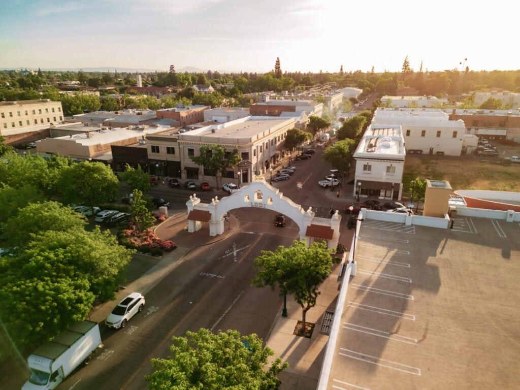Lodi, CA downtown street view with historic buildings and trees at sunset.